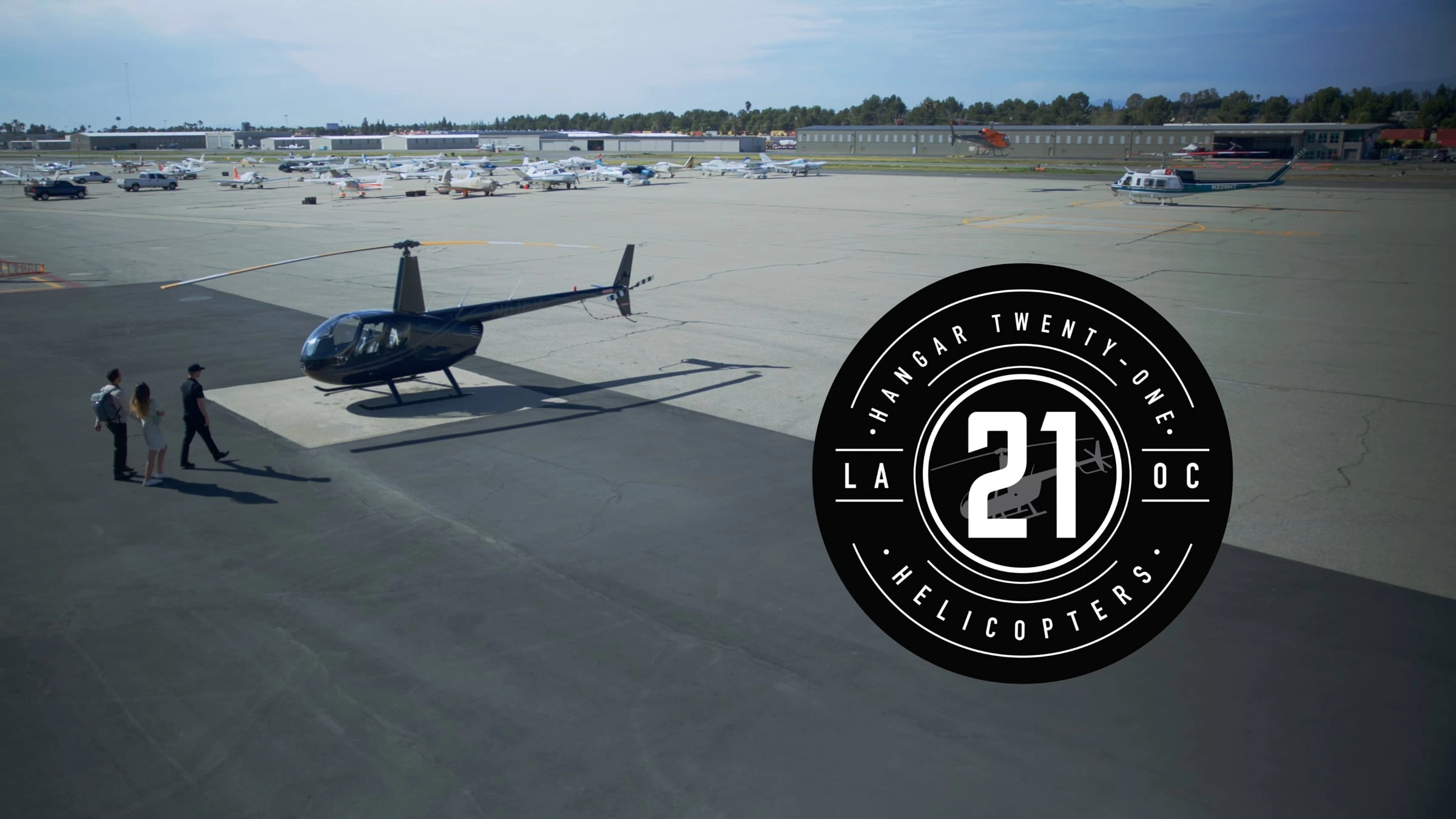 Helicopter on airport tarmac with Hangar 21 logo.